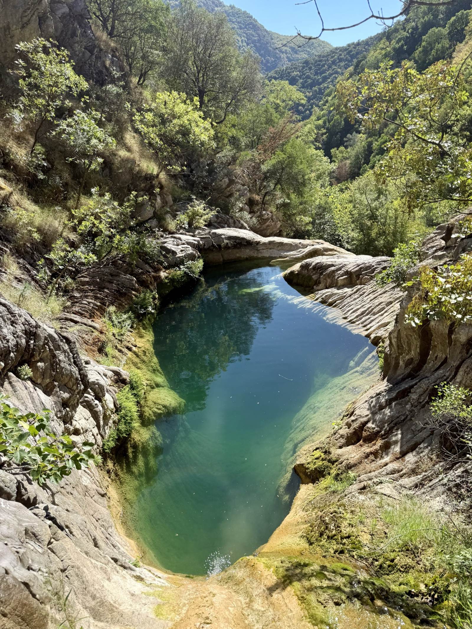 Deep emerald pool held between smooth limestone walls in Drenostica Canyon